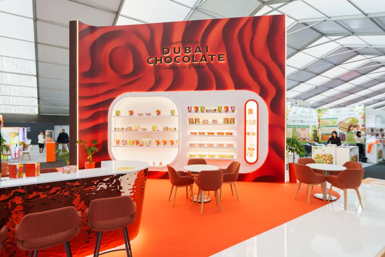 The red Dubai Chocolate display wall and illuminated product shelves
